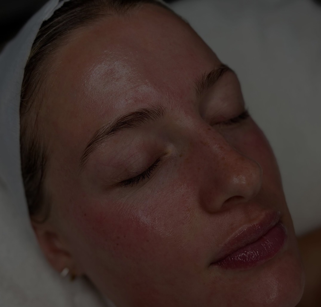 A client relaxing on the treatment couch, eyes closed, skin glowing after a facial